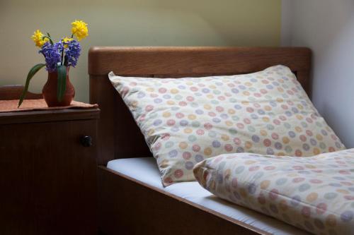 a pillow and a vase of flowers on a bed at Pension Kezele in Graberje Ivanićko