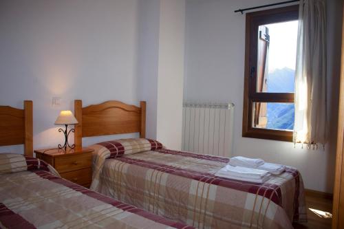 una camera da letto con due letti e una finestra di Apartamentos Ball Benas Edificio Aigualluts a Cerler