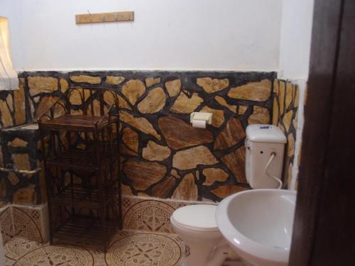 a bathroom with a stone wall and a toilet and sink at SALEM Eco-Lodge & Guesthouse in Mbale