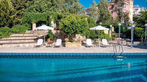 uma piscina com cadeiras, mesas e guarda-sóis em Villa Andromeda em Chania