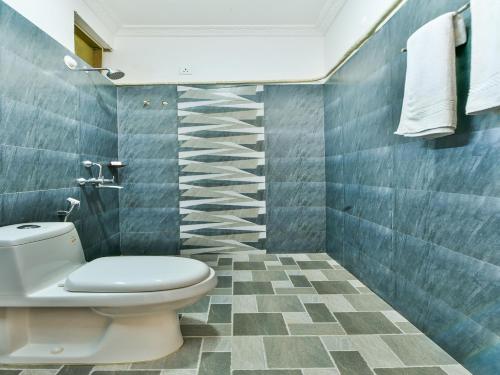 a bathroom with a toilet and blue tiled walls at OYO 15836 River Front Resort in Morjim