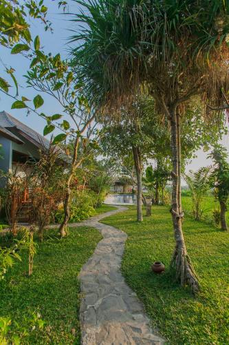 a path through a garden with a palm tree at Villa D'Carik Bali in Denpasar