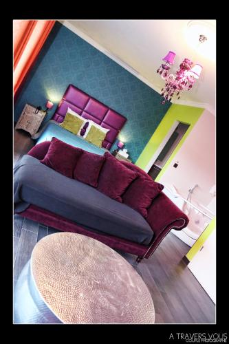 a bedroom with a large bed with purple pillows at V E R O N E - Rooms & Suites - Liège - Rocourt in Liège