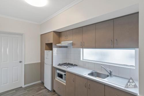 a kitchen with a stove, sink and refrigerator at Esperance Bay Holiday Park in Esperance
