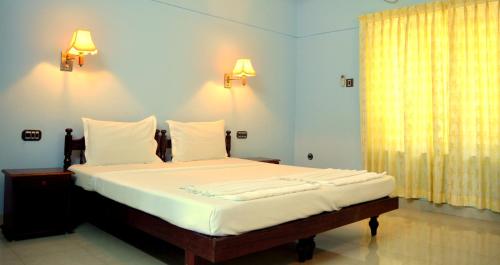 可瓦蘭的住宿－Ganesh Ayurveda Holiday Home bed and breakfast，一张位于带两盏灯和一扇窗户的房间的床铺