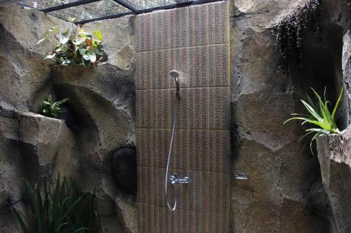 a metal shower in a stone wall with plants at Sekumpul Accommodation in Singaraja
