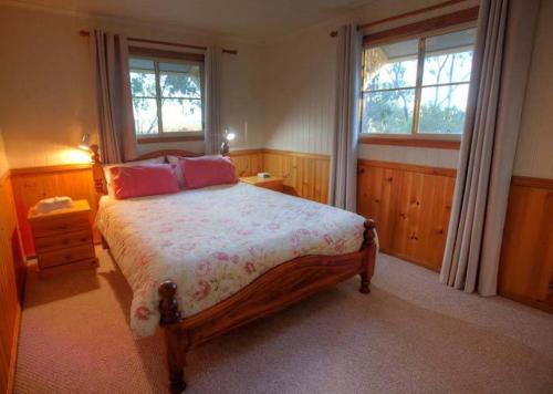 a bedroom with a large bed and two windows at Accommodation Creek Cottages & Sundown View Suites in Ballandean