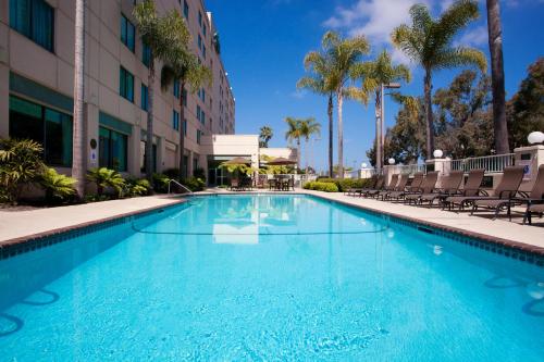 a swimming pool at a hotel with chairs and palm trees at Country Inn & Suites by Radisson, San Diego North, CA in Mira Mesa
