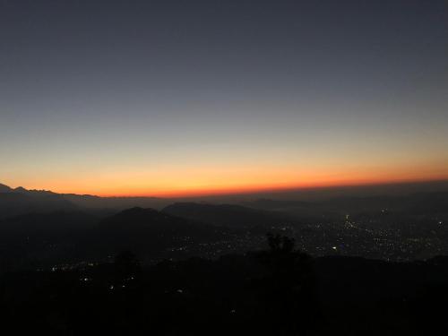 a view of a city at sunset from a mountain at Hotel Pristine Himalaya in Pokhara
