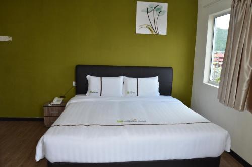 a bedroom with a large white bed with green walls at Riverview Hotel in Bahau