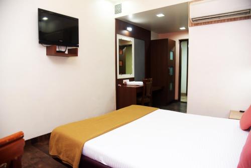 a hotel room with a bed and a flat screen tv at Hotel Indiana Inn in Navi Mumbai