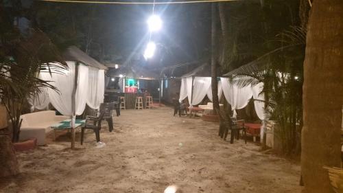a room with tables and chairs at night at Little Nest in Mandrem