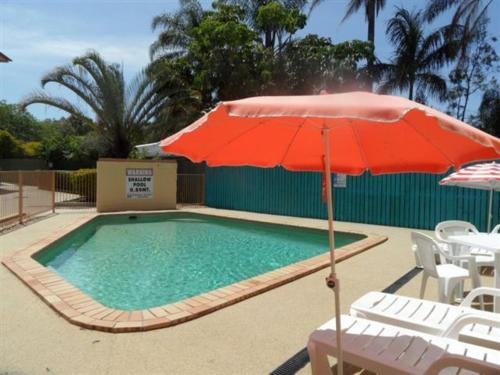 a pool with a red umbrella and a table and chairs at Sylvan Beach Resort in Bellara