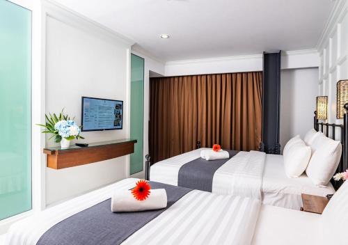a hotel room with two beds and a television at Dang Derm In The Park Khaosan in Bangkok