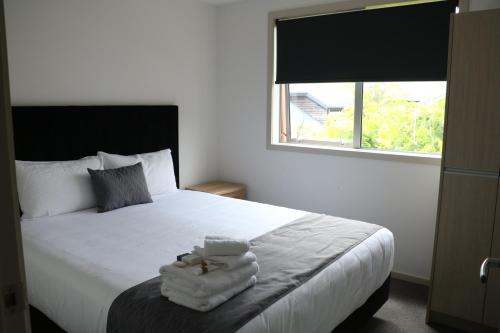 a bedroom with a bed with towels on it at MCM Motel Christchurch in Christchurch