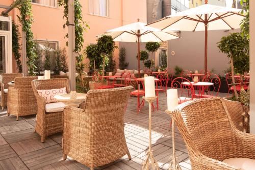 um pátio exterior com mesas, cadeiras e guarda-sóis em Maxime Hotel Lisbon em Lisboa