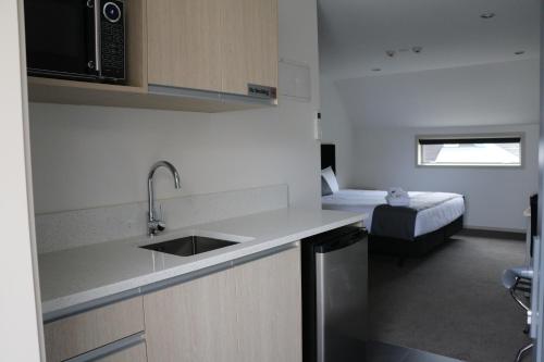 a kitchen with a sink and a room with a bed at MCM Motel Christchurch in Christchurch