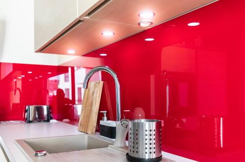 a kitchen with a sink and a red wall at Apartament Brandy in Szczecin