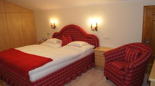 a bedroom with a red bed and a chair at Pension Hartenfels in Lech am Arlberg