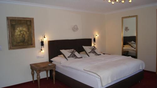 a bedroom with a large white bed and a mirror at Pension Hartenfels in Lech am Arlberg