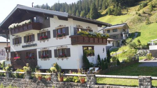 a white house with flower boxes on its windows at Pension Hartenfels in Lech am Arlberg