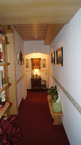 a hallway with a red carpet and a room with a table at Pension Hartenfels in Lech am Arlberg