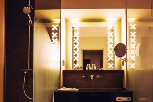 uma casa de banho com um lavatório e um espelho grande em Thehotel at LIPPISCHER HOF em Bad Salzuflen