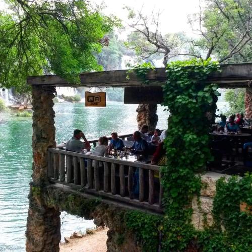 a group of people sitting at a restaurant next to the water at Spacious 80m2 Apartment in the Center in Ljubuški
