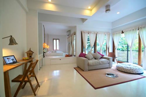 a living room with a couch and a desk and some windows at Proud Phu Fah Maerim Resort in Mae Rim