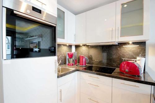 une cuisine avec des armoires blanches et un appareil rouge sur le comptoir dans l'établissement Villa Allegra, à Binz