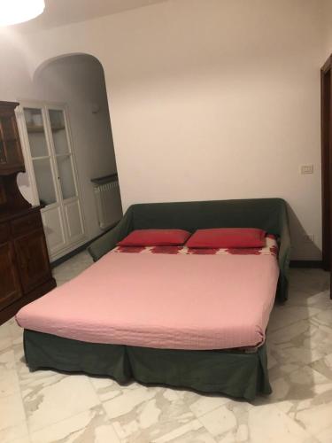 Schlafzimmer mit einem Bett mit rosa Bettwäsche und roten Kissen in der Unterkunft Appartamento via Roma 56 in Monterosso al Mare