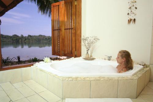 Eine Frau, die in einer Badewanne neben einem Fenster sitzt. in der Unterkunft Seachange Lodge in Port Vila