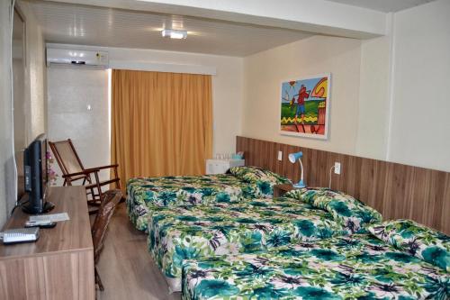 a hotel room with two beds and a television at Hotel Casa De Praia in Fortaleza