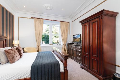 a bedroom with a bed and a dresser and a television at Bron Eifion Hotel in Criccieth