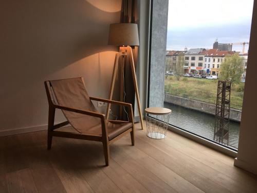 a chair and a lamp in a room with a window at Skyline Flats Gent in Ghent