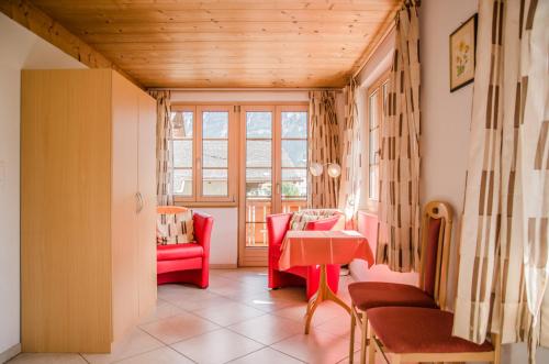 a living room with a table and red chairs at Apartment Strassscheuer 3.5 - GriwaRent AG in Grindelwald