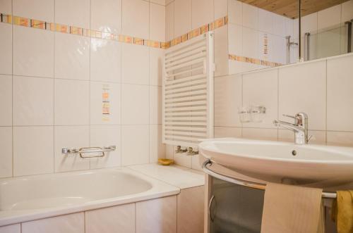 ein weißes Badezimmer mit einem Waschbecken und einer Badewanne in der Unterkunft Apartment Strassscheuer 3.5 - GriwaRent AG in Grindelwald