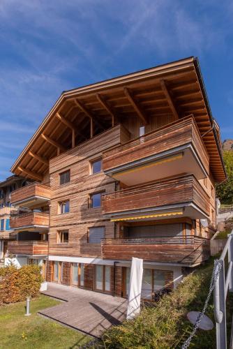 a building with a wooden facade on a hill at Chalet Am Acher 7 in Wengen