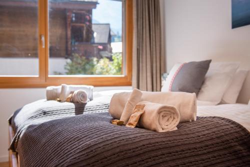 a bed with blankets and pillows on it with a window at Chalet Am Acher 7 in Wengen