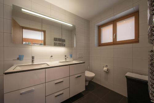 a bathroom with a sink and a toilet and a mirror at Chalet Am Acher 7 in Wengen