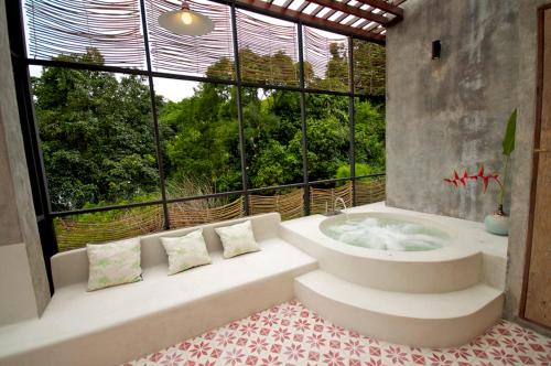 a bathroom with a tub and a large window at Proud Phu Fah Maerim Resort in Mae Rim