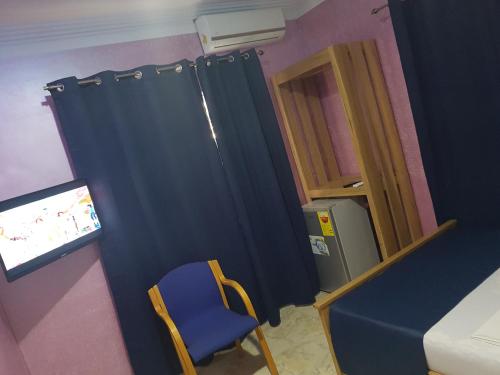 a room with a blue curtain and a blue chair at Homey Lodge in Kumasi