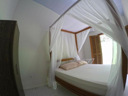 a bedroom with a canopy bed with white drapes at Casa em Pipa 2 quartos in Pipa