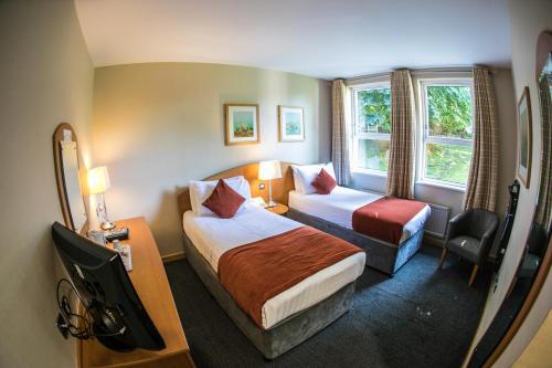 um quarto de hotel com duas camas e uma televisão em Rosspark Hotel Kells em Ballymena