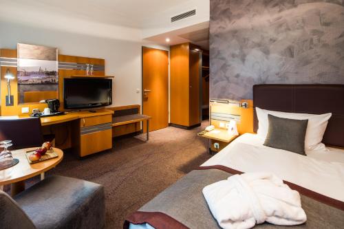 a hotel room with a bed and a flat screen tv at Ramada by Wyndham Dresden in Dresden
