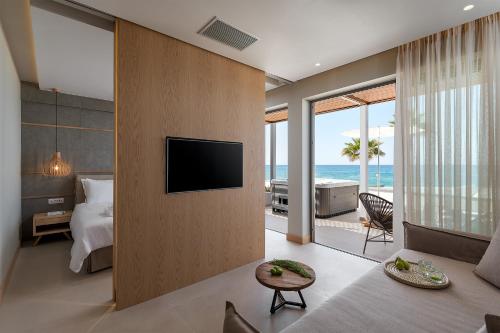 a hotel room with a bed and a television and the ocean at Ikones Seafront Luxury Suites in Rethymno Town