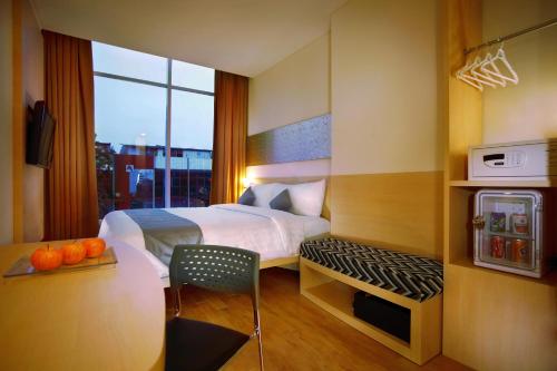 a hotel room with a bed and a desk with a stove at Neo Hotel Melawai by ASTON in Jakarta
