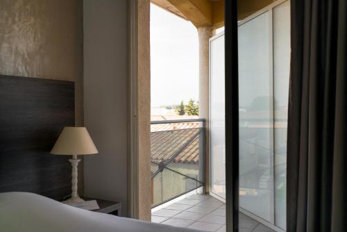 a bedroom with a bed and a large glass window at Hôtel Ariane in Istres