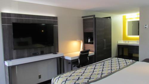 a bedroom with a bed and a desk and a tv at Baymont by Wyndham Murfreesboro in Murfreesboro