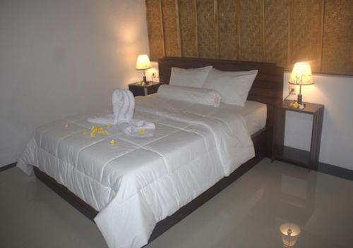 a bedroom with a large white bed with two lamps at Sebrang Hills Bungalow in Nusa Penida